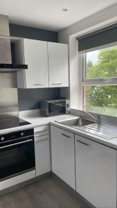 贝尔法斯特CityGo Apartments Queens Wellington的厨房配有白色橱柜、水槽和窗户。