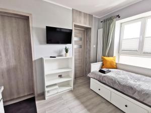 格丁尼亚Apartamenty Fińska Gdynia的卧室配有一张床,墙上配有电视。