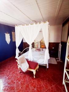 罗萨里奥港Kikiki House的一间卧室配有一张天蓬床和一把椅子