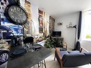 蓬拉贝Le petit atelier - Studio - WIFI - Coeur de ville - Parking的客厅配有桌子和墙上的时钟