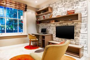 伦敦康福特茵维多利亚酒店的客厅配有电视和挂有图画的墙壁