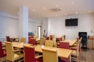 伦敦Comfort Inn Edgware Road的一间带桌椅和电视的用餐室
