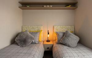 BurgheadThe Beach Hut, Burghead的一间卧室设有两张床和一张桌子上的台灯。