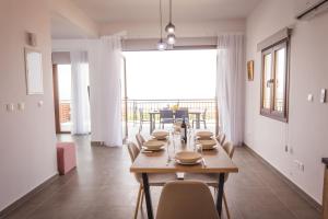 LysoVilla Aeria的一间带桌椅和大窗户的用餐室