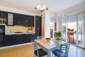 安杰拉Iris Apartment Lago Maggiore的厨房配有黑色橱柜和桌椅