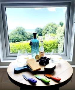 文特诺Lottie's Lookout, Ventnor with fantastic Sea Views的一张带瓶子的木桌和窗户