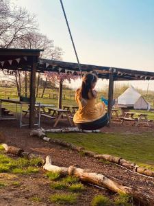 莱肯希思Willow Grove Farm Glamping的坐在公园秋千上的女孩