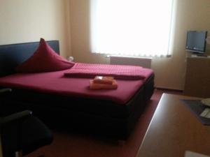 Ostrau祖尔林德酒店的一间卧室配有一张带红色床单的床和一扇窗户。
