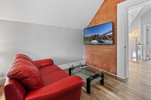 基奇纳ENTIRE 3-UNITS TOP-FLOOR ACROSS FROM GOOGLE的客厅里的一个红色沙发,砖墙上配有电视