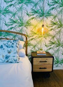 彼得马里茨堡Mdumela Stays 2 Bedroom Modern City Apartment的一间卧室配有一张带床头柜的床和植物墙