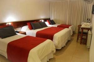 格塞尔镇Intersur Villa Gesell的酒店客房带两张红色和白色的床单