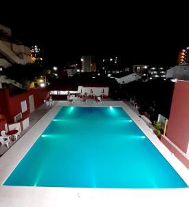 格塞尔镇Intersur Villa Gesell的夜间在大楼顶部的蓝色游泳池