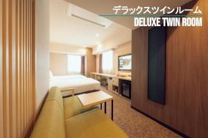 仙台Henn na Hotel Sendai Kokubuncho的酒店客房配有床、沙发和电视。