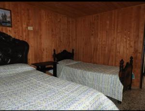 圣罗莎德卡瓦尔Hostal San Ramon的木镶板客房内的两张床