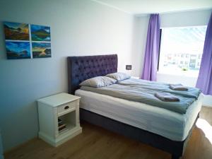 BolungarvíkApartment with Amazing Mountain View的一间卧室配有一张床和一个带紫色窗帘的窗户