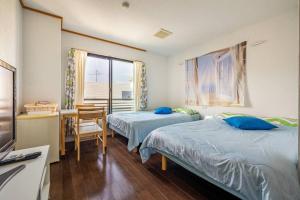 KawanaMR. TOMO KAWANA的一间卧室设有两张床、一张桌子和一个窗口。