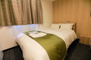 大阪Tabist Hotel Asiato Namba的一间卧室配有一张带绿色和白色毯子的床