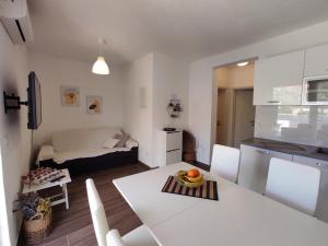 拉斯托伏Apartman Portorus的厨房以及带白色桌椅的起居室。