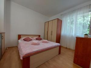 UbliApartman Nora的一间卧室配有一张带粉色床单的床和一扇窗户。