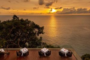 卡马拉海滩Paresa Resort Phuket - SHA Extra Plus的甲板上配有遮阳伞的日落