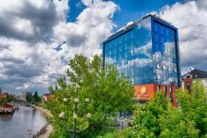比得哥什Focus Hotel Premium Bydgoszcz的河边的一座高大的玻璃建筑
