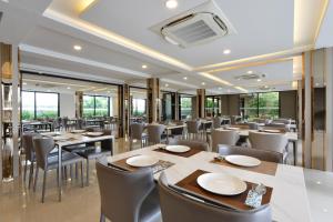 莱卡邦Grand BS Airport Hotel Suvarnabhumi的餐厅设有桌椅和窗户。