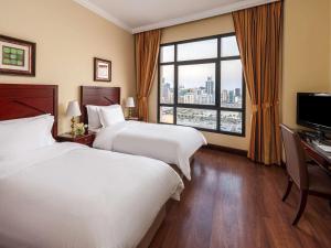 麦纳麦Mercure Grand Hotel Seef - All Suites的酒店客房设有两张床和窗户。