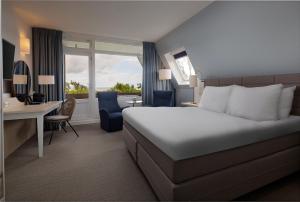 东弗利兰瓦登韦斯特考得酒店的酒店客房设有一张大床、一张书桌和一张书桌。