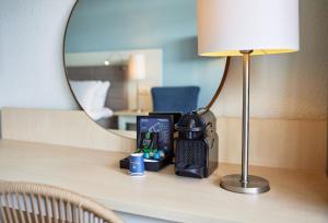 东弗利兰瓦登韦斯特考得酒店的一张带灯和镜子的酒店客房桌子