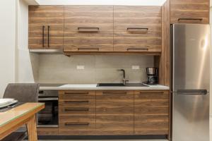 海若克利欧Athena Apartment的厨房配有木制橱柜和不锈钢冰箱。