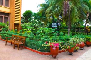 阿克拉Coconut Grove Regency Hotel的种有长凳、鲜花和植物的花园