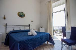 阿马尔菲丰塔纳酒店的一间卧室配有一张带蓝色毯子的床和窗户。
