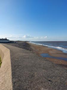 斯凯格内斯6 berth static caravan, sealands holiday park ingoldmells, skegness的海边的海滩,有一面挡墙