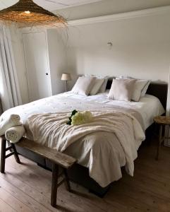 达默De Bijenkorf的卧室配有一张白色大床和长凳