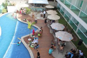 卡波布里奥Paradiso Peró Praia Hotel的一群人坐在游泳池边,拿着遮阳伞