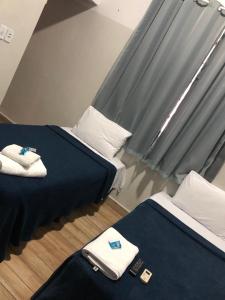 里奥韦尔迪Ágape Hotel的配有两张床铺的客房配有蓝色床单和白色枕头