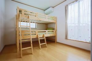 Agarii名護ビーチハウス的一间卧室配有双层床、一张桌子和一个窗户。