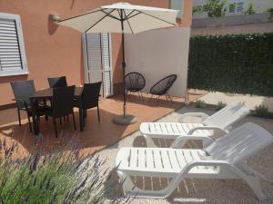 特罗吉尔Tomena apartments的庭院配有桌椅和遮阳伞。