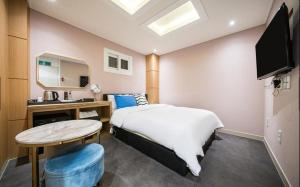 釜山Bay 202 Hotel的一间卧室配有一张床、一张桌子和一面镜子