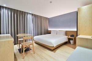 蔚山Custom Hotel的酒店客房配有一张床铺和一张桌子。