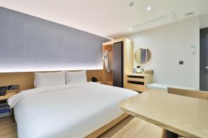 蔚山Custom Hotel的卧室配有一张白色的大床和一张桌子