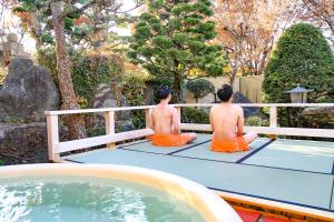 盐尻市Kur and Hotel Shinshu的两个男人坐在游泳池旁的网球场上