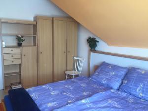 德布勒森Barátságos ház emelete的一间卧室配有一张带蓝色床单的床和一把椅子