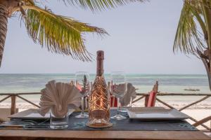 江比阿Mamamapambo Boutique Hotel的海滩上一张桌子,上面放着一瓶和眼镜