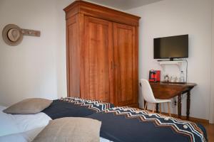 埃圭斯海姆Le Hameau d'Eguisheim - Chambres d'hôtes & Gîtes的一间卧室配有一张床、一张书桌和一台电视