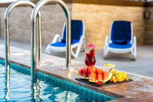 沙迦Luxe Grand Hotel Apartments的坐在游泳池旁的水果盘