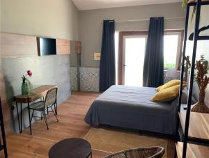 阿尔布费拉Lost & Found - Guesthouse & Suites的一间卧室配有一张床、一张桌子和一个窗户。