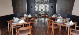 纳加阔特Kavya Resort & Spa的一间设有木桌和椅子的餐厅