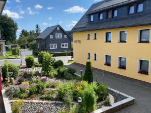 CursdorfHotel Im Kräutergarten的黄色建筑前的花园