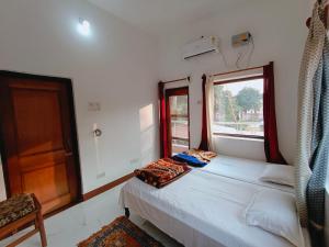菩提伽耶The Gupta Guest House的一间小卧室,配有两张床和窗户
